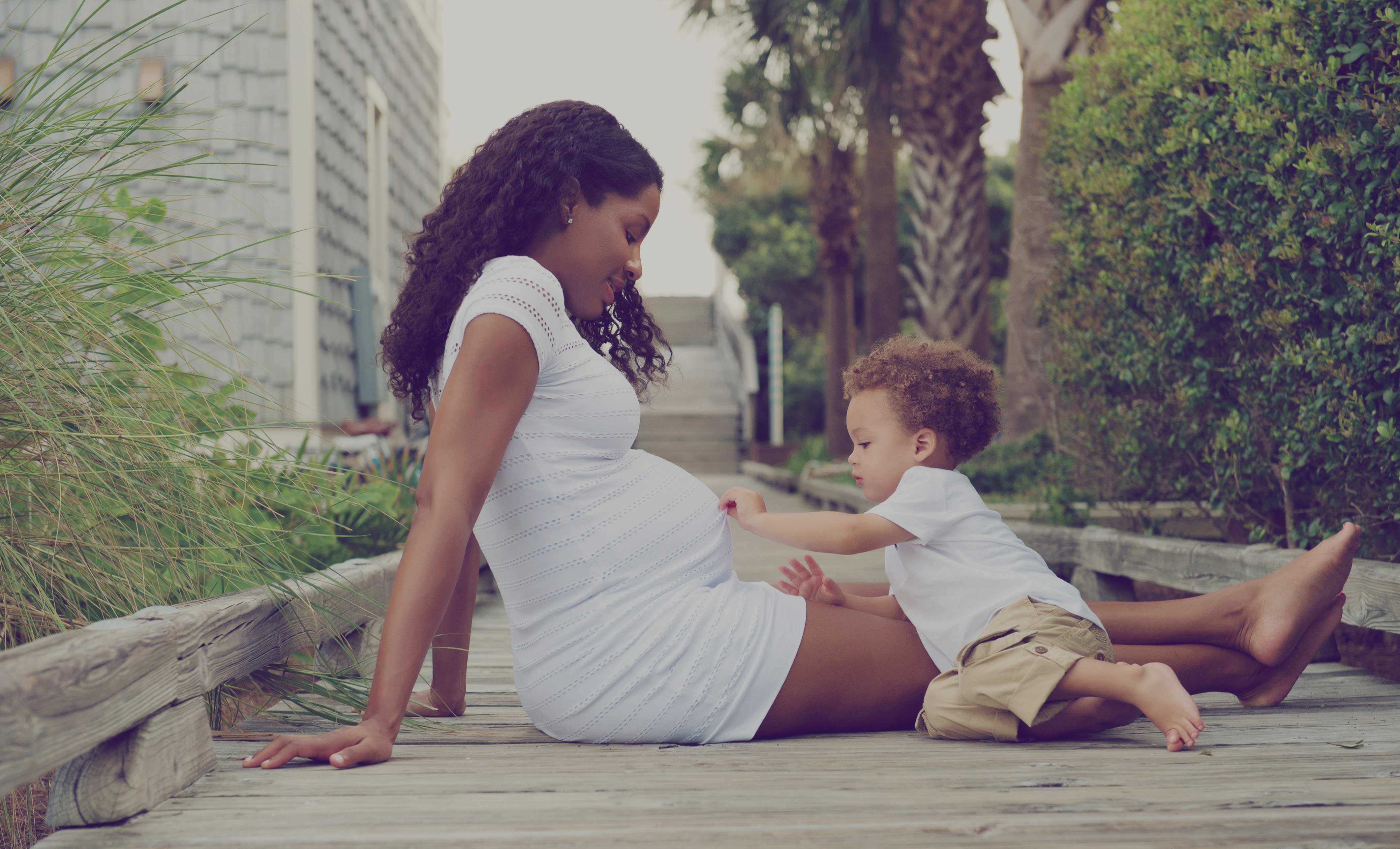 A pregnant mom and her son outdoors.