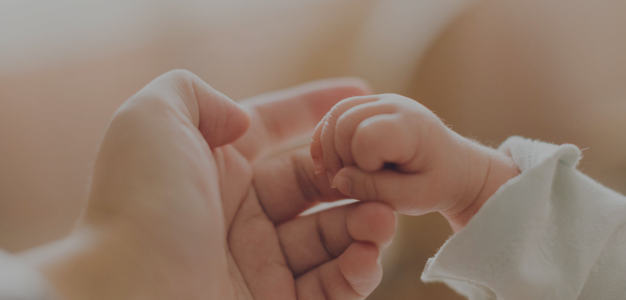 A baby holding one of her mother's fingers