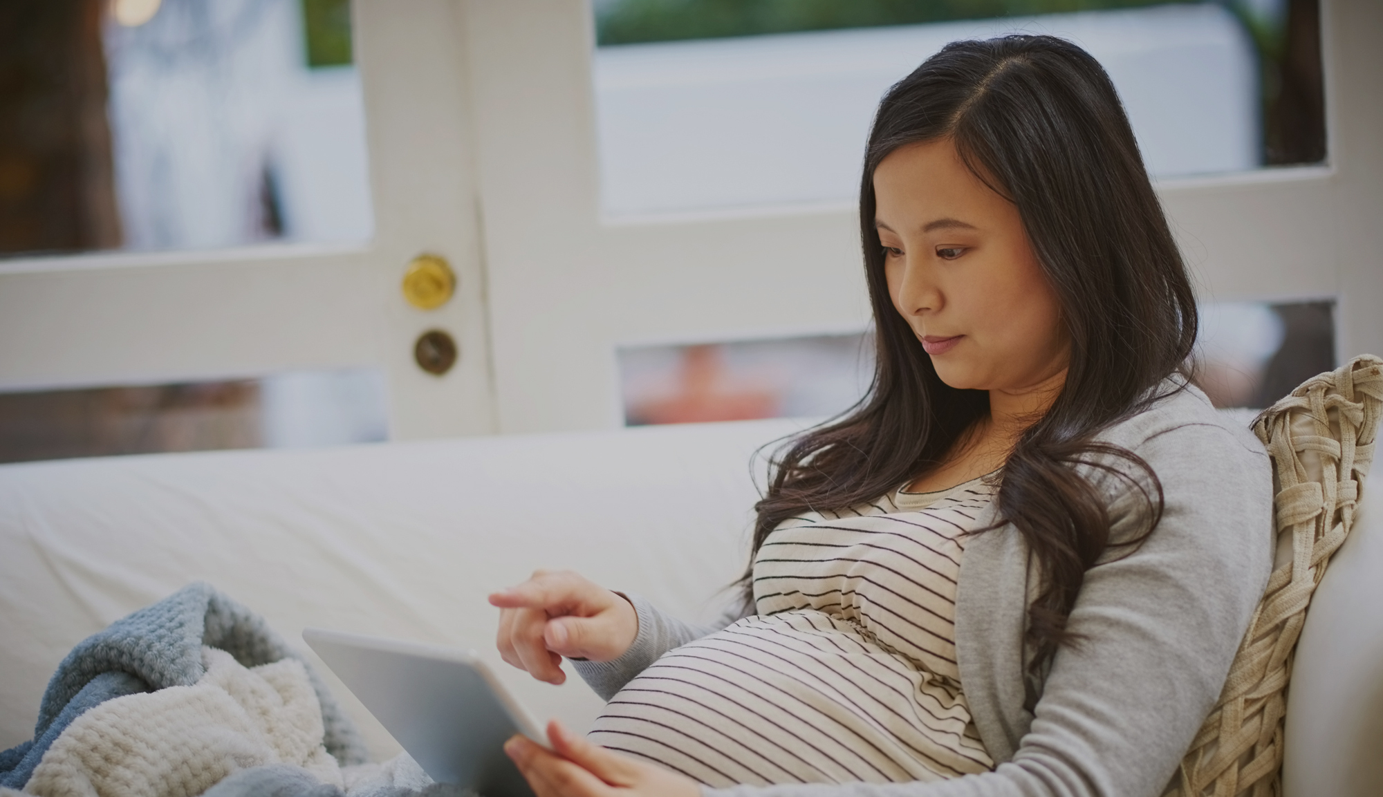 Expecting mother using an iPad to connect with the AdventHealth Birth Experience Team